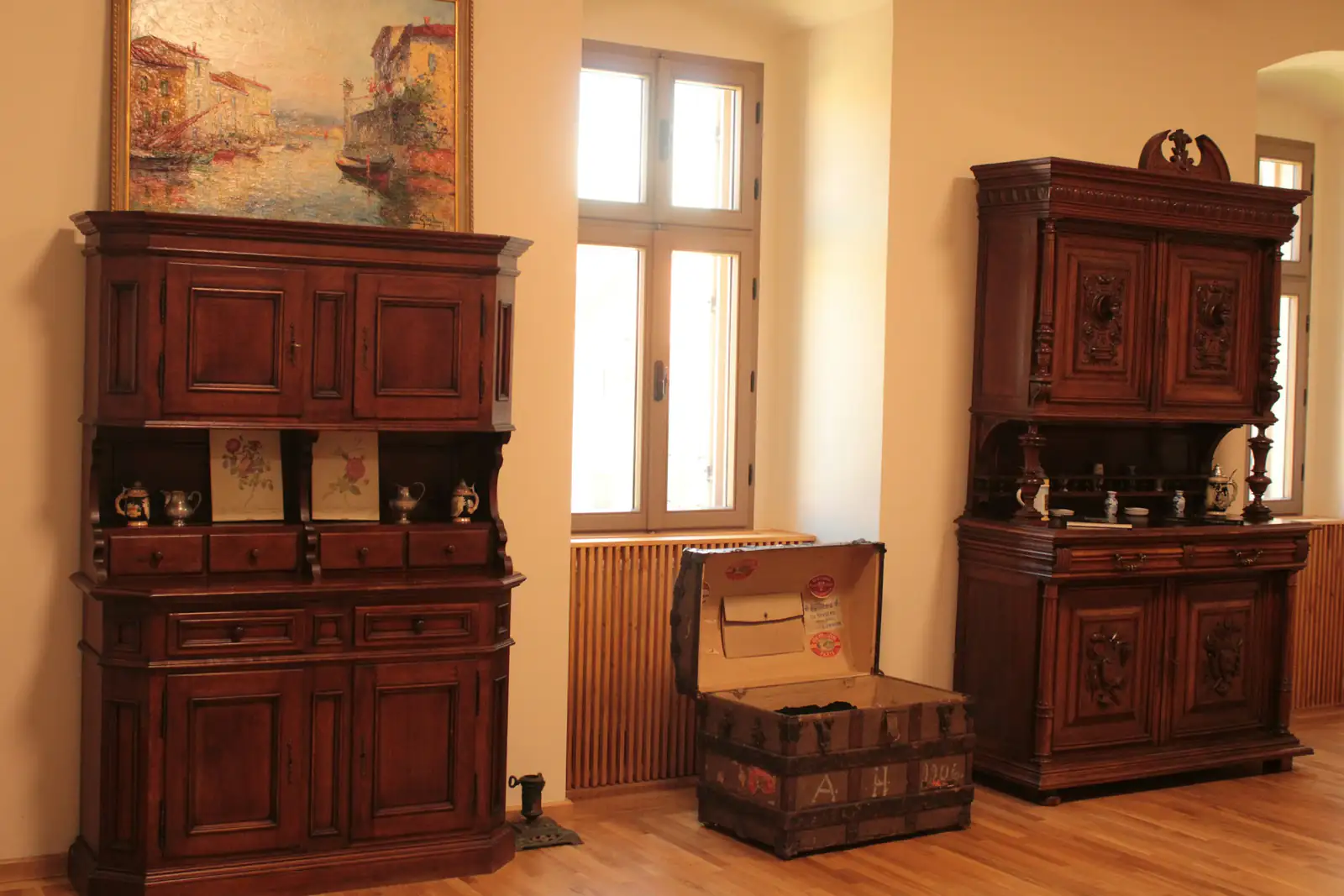 Zwei geschnitzte Holzbuffets und eine alte Reisetruhe in einem hellen Zimmer